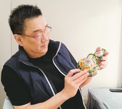 骨董工芸品を手にする創業者・翟健民氏